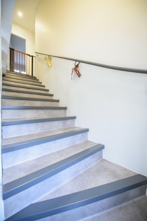 escalier à quart tournant moderne avec main courante en acier et marche habillage béton
