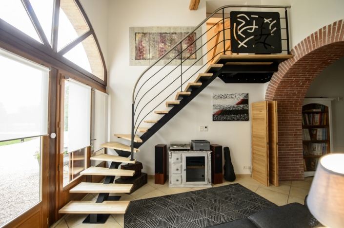 salon avec escalier quart tournant en bois et limon central en metal